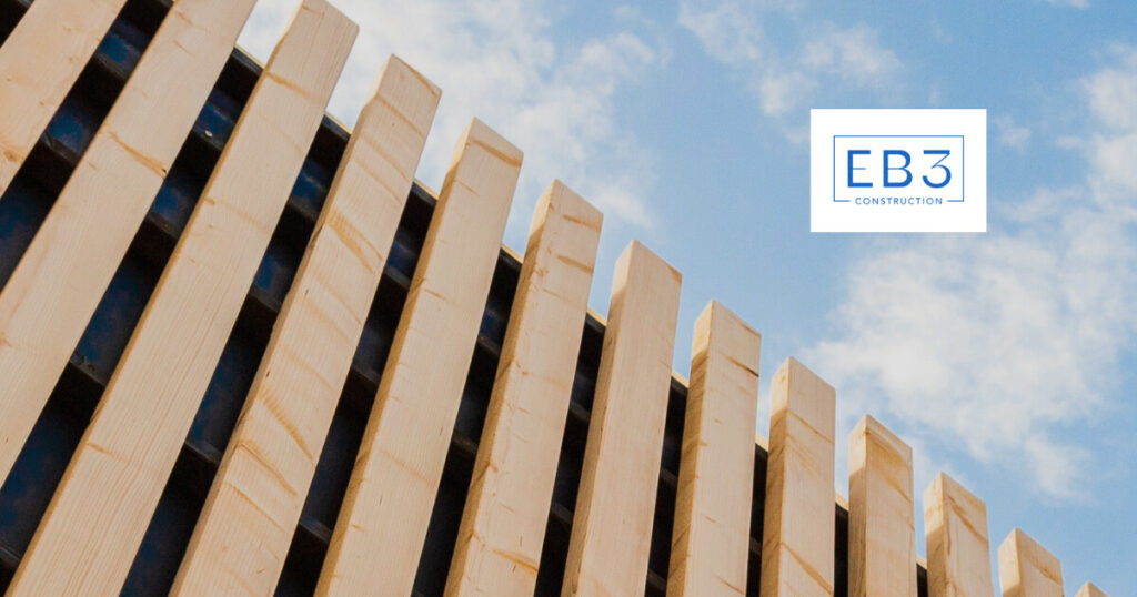 Wooden beams of a construction structure rise against a blue sky.