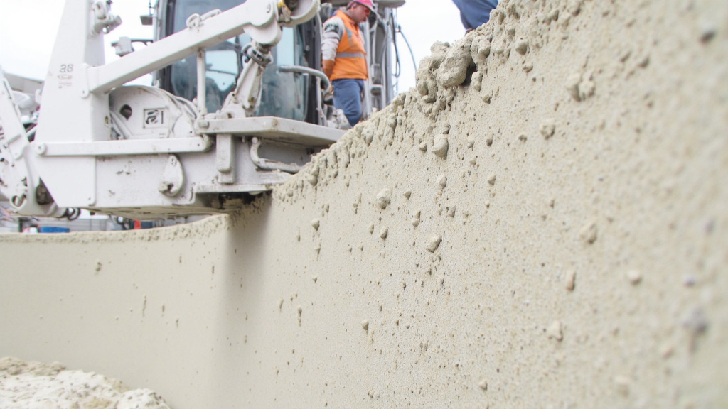 Close-up of 3D-Printed Concrete Wall Close-up of a 3D-printed concrete wall being created on-site with a worker operating advanced machinery.