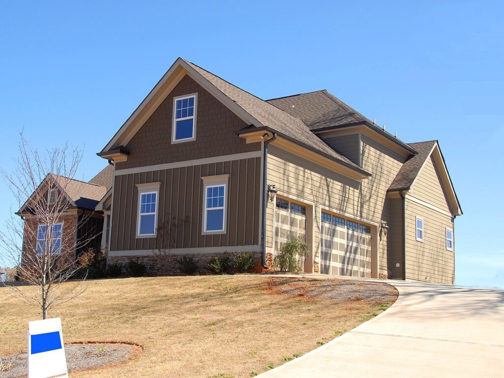 A large modern house with a three-car garage and a clear blue sky.