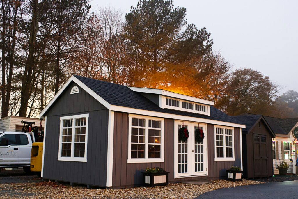 A small gray cabin with white trim is decorated with wreaths.