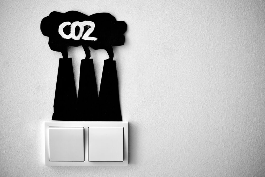 Black paper cutouts of smokestacks with "CO2" above a light switch.
