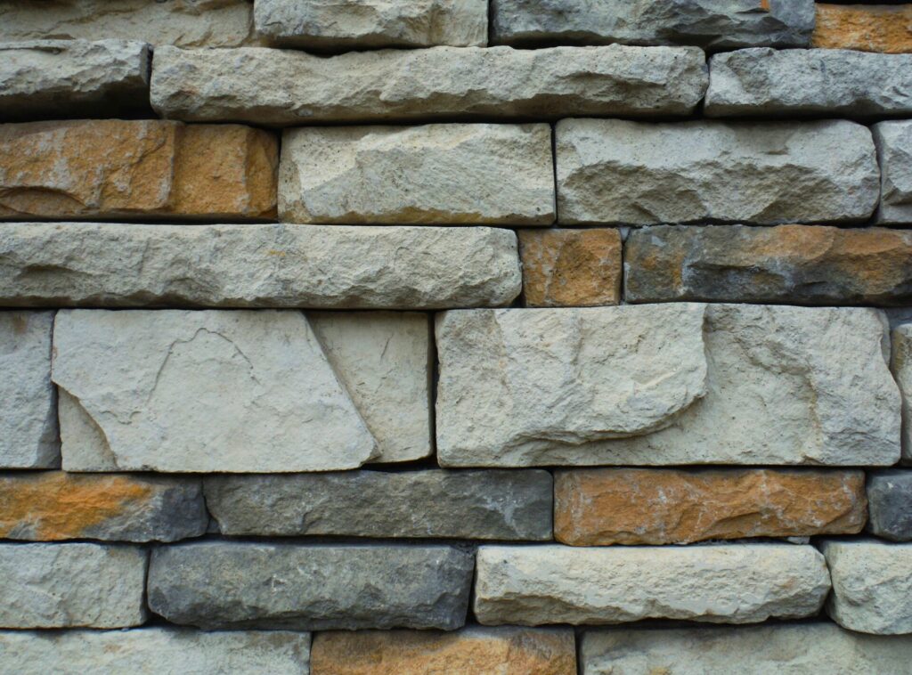 Close-up of a textured stone wall with rectangular beige and gray blocks.