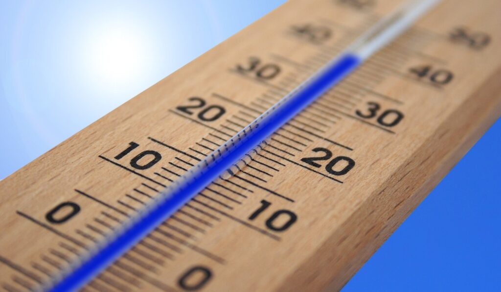 Close-up of a wooden thermometer displaying a temperature above 20 degrees Celsius.