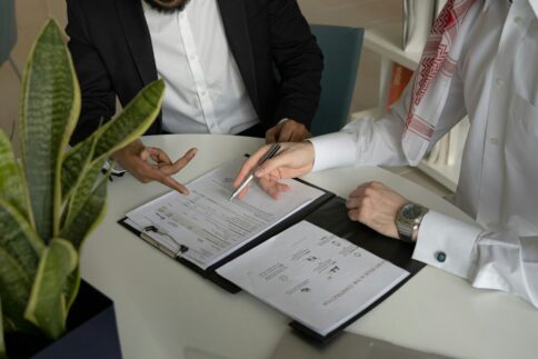 Two people reviewing documents on a table in a business setting.