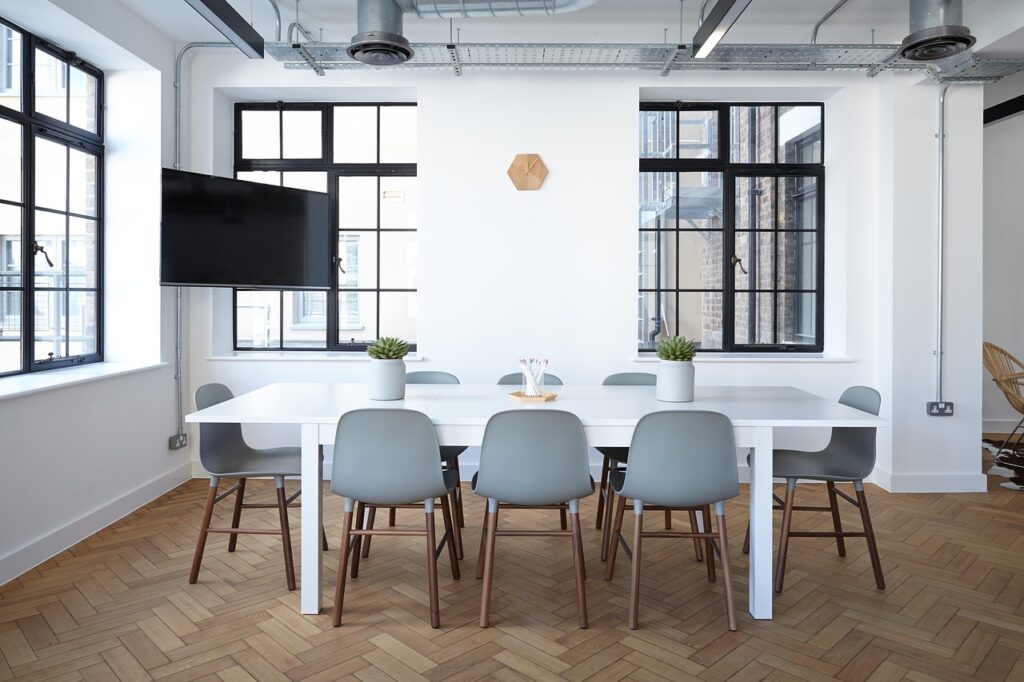 A modern conference room with a white table and gray chairs.