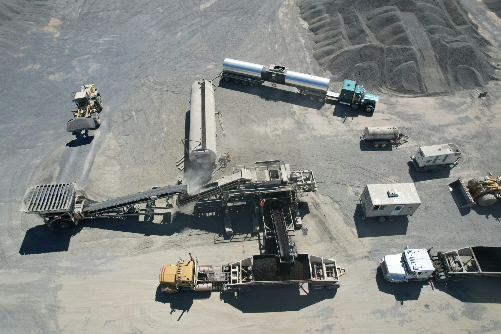 Heavy Machinery at Work in a Construction Site Aerial view of a construction site with heavy machinery and trucks handling gravel.