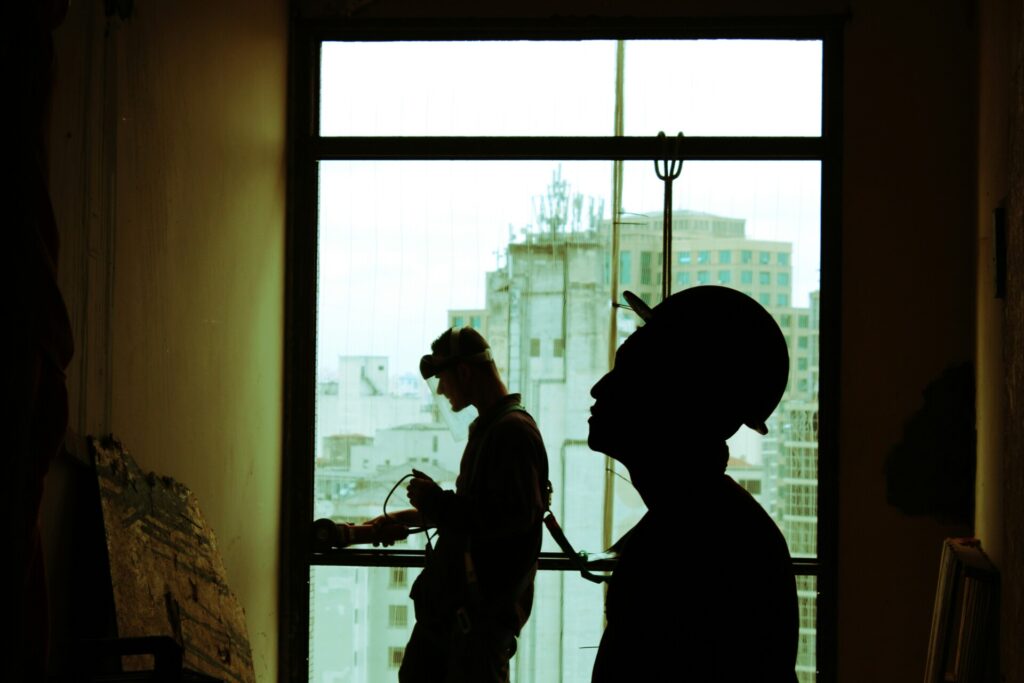 Silhouette of two construction workers with a city skyline in the background.