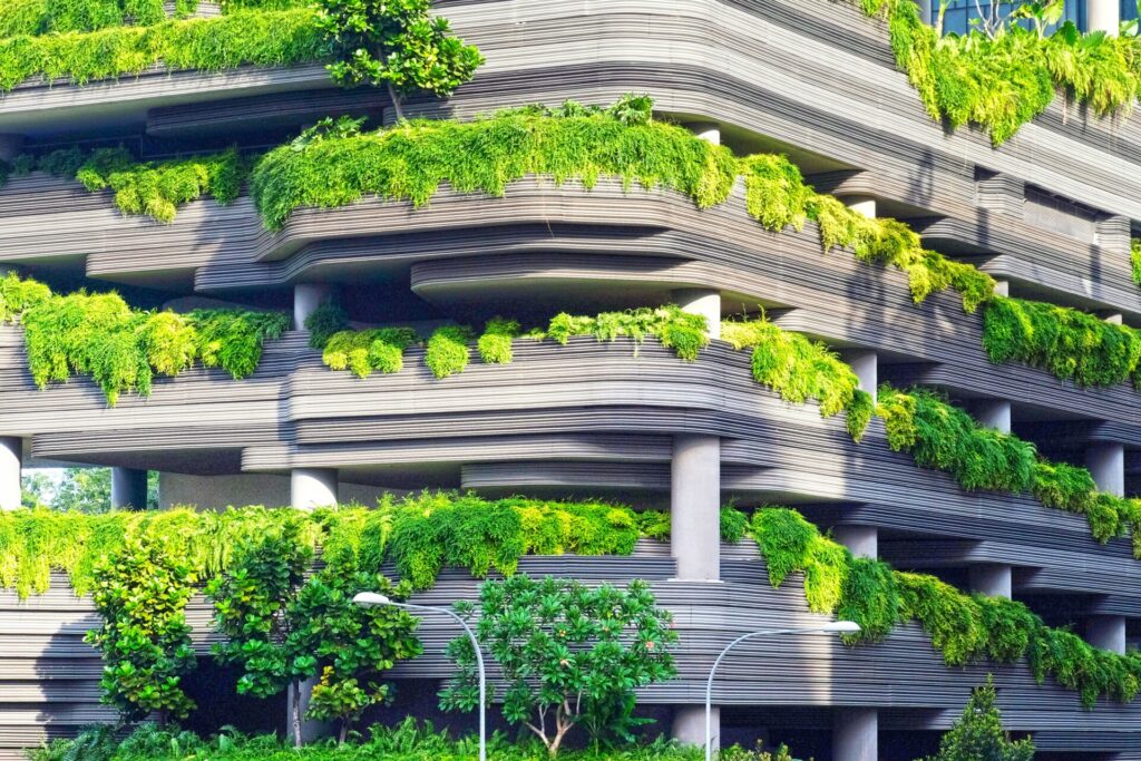 A modern building facade with lush green plants cascading over ledges.