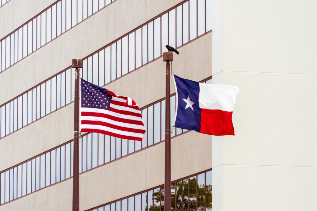 American and Texas flags waving in front of a building