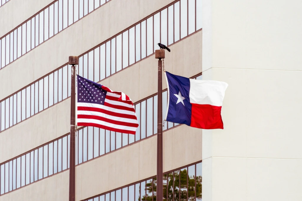 American and Texas flags waving in front of a building