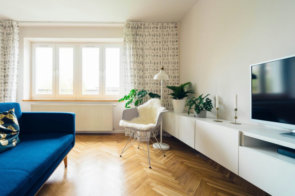 A modern living room with blue sofa, TV, and large window.