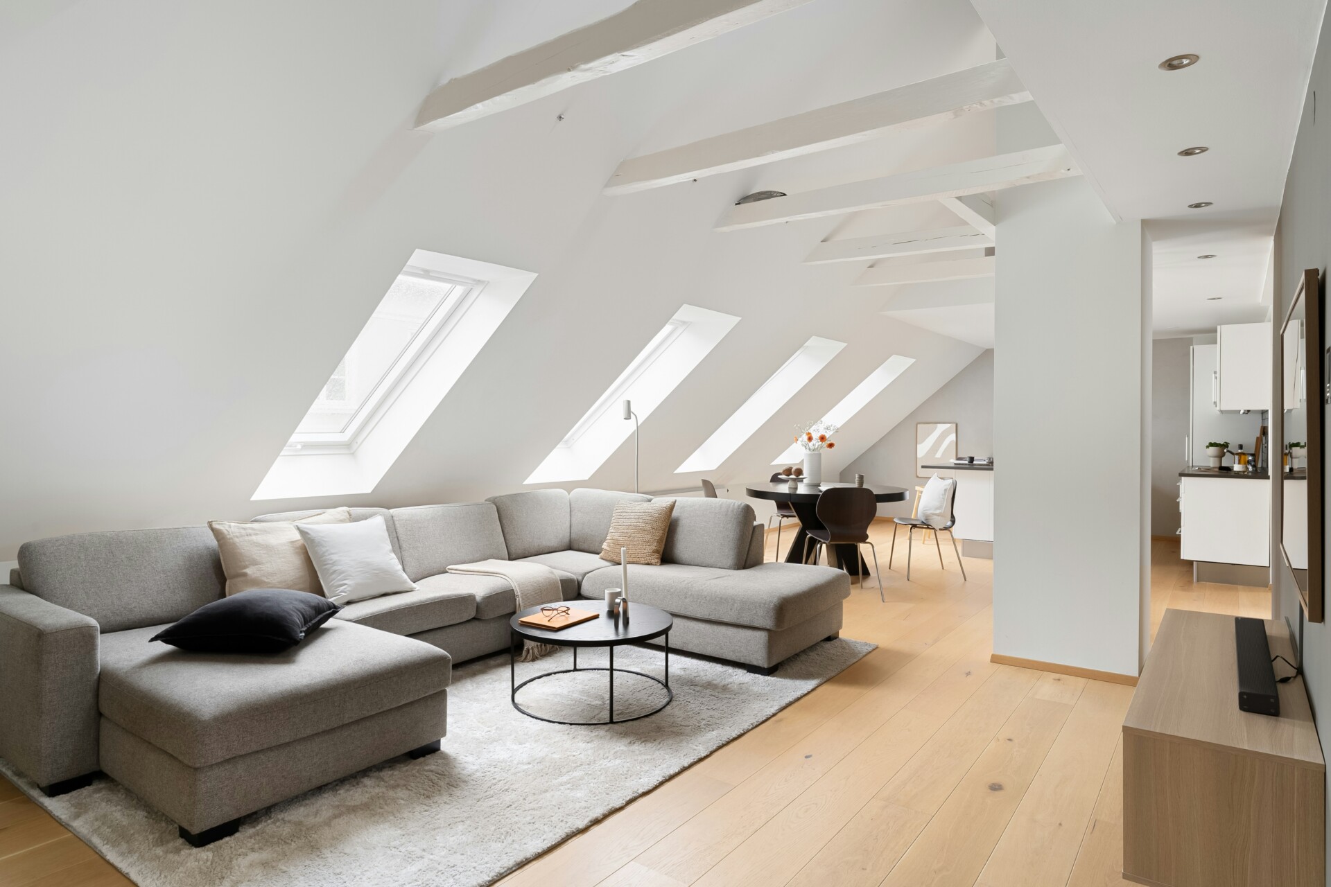 Stylish Modern Living Room A spacious modern living room with a gray sectional sofa, a black circular coffee table, and large skylight windows.