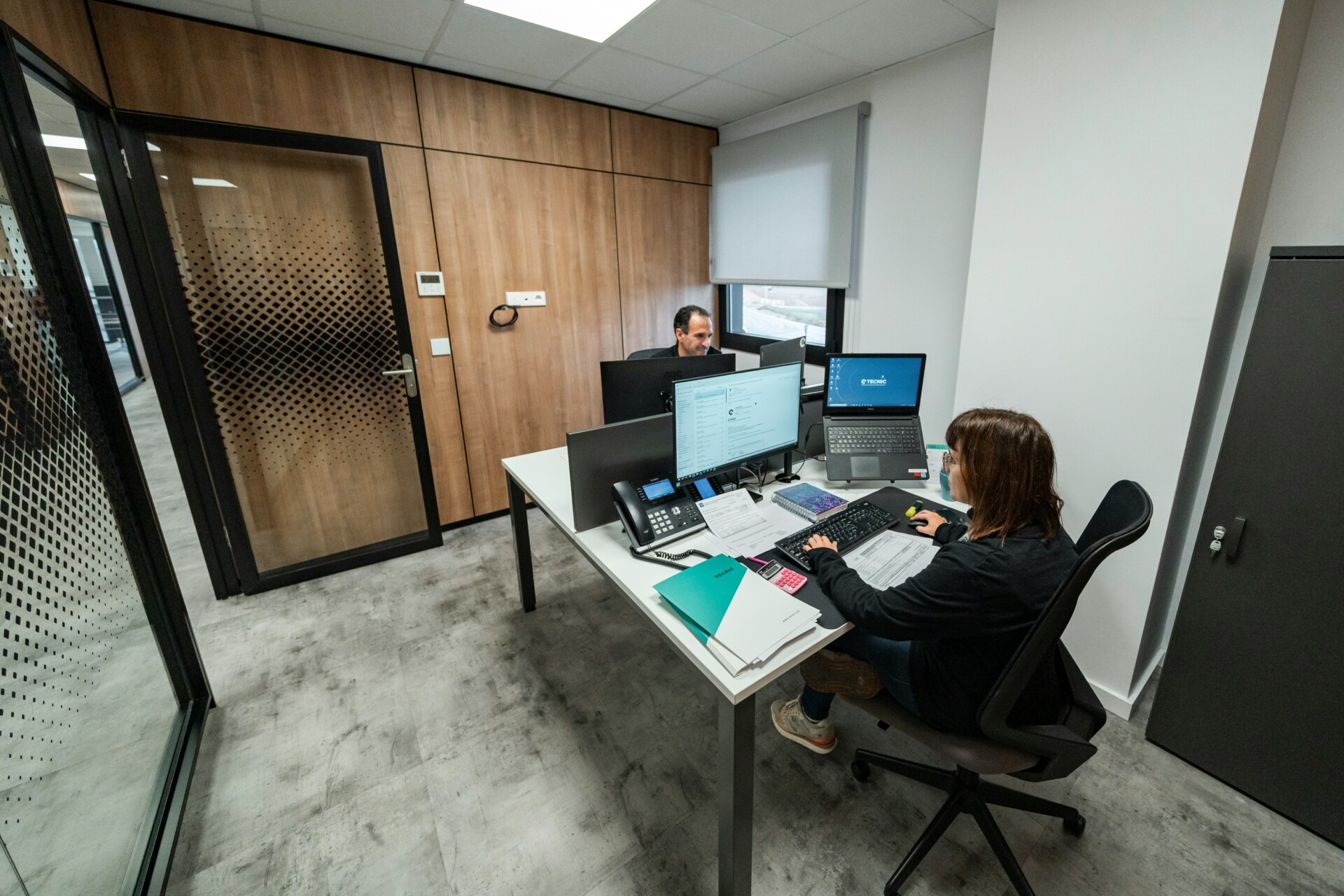 Collaboration in a Modern Office A modern office setting with two employees working at desks with computers.