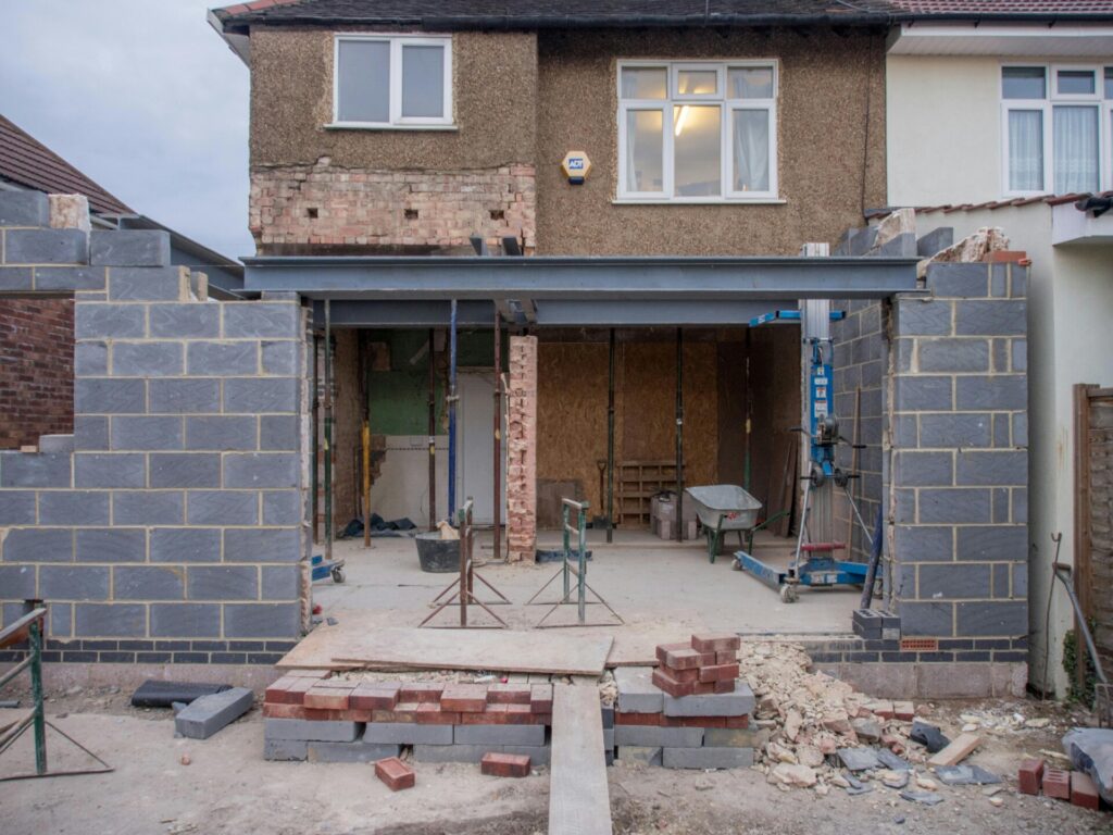 A house extension under construction with exposed bricks and scaffolding.