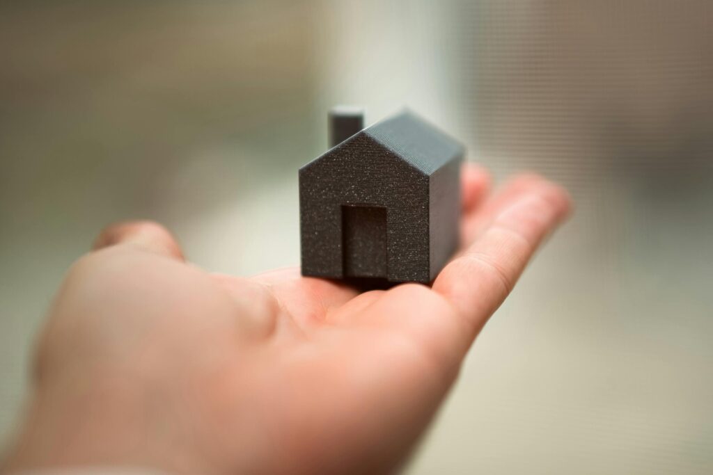 A small house model rests in the palm of a person's hand.