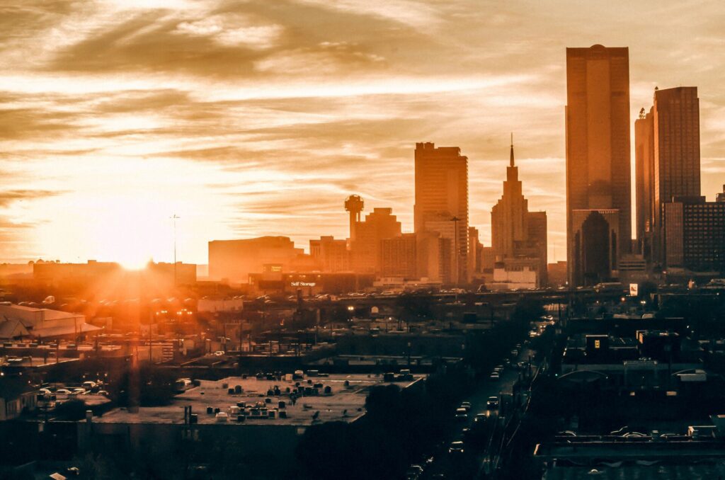 Sunset over a city skyline with skyscrapers and a dramatic sky.