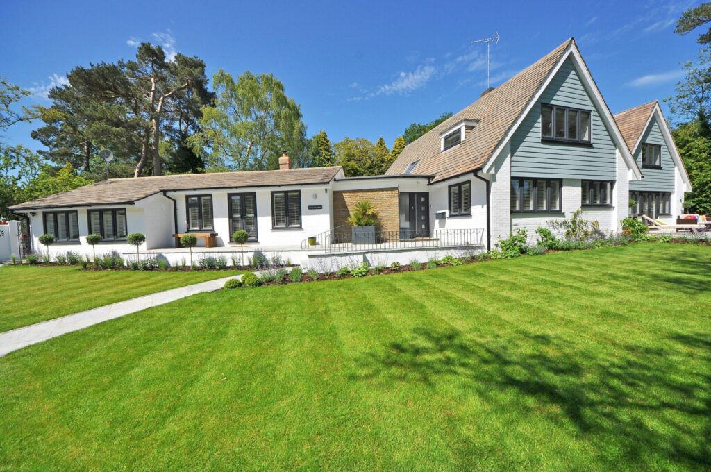 A modern house with a well-maintained lawn under a clear blue sky.