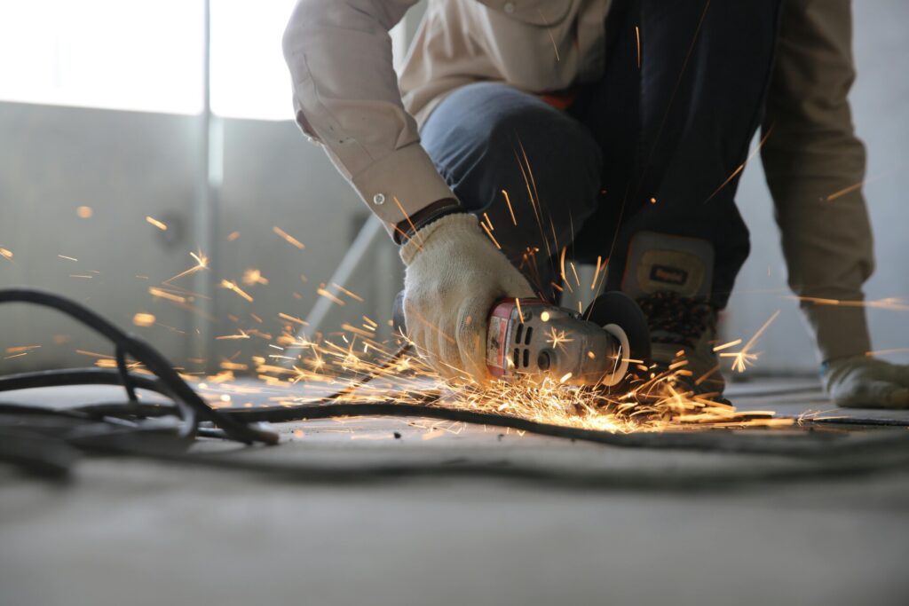 Worker using an angle grinder, creating sparks in an industrial setting.