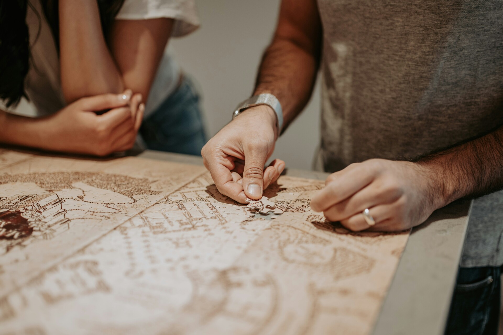 Teamwork in Puzzle Solving Two people working together on a puzzle featuring a detailed map.