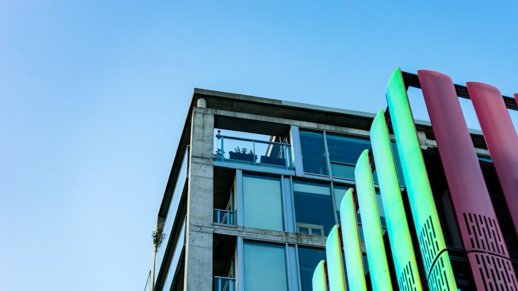 A modern building corner with colorful architectural panels against a clear sky.