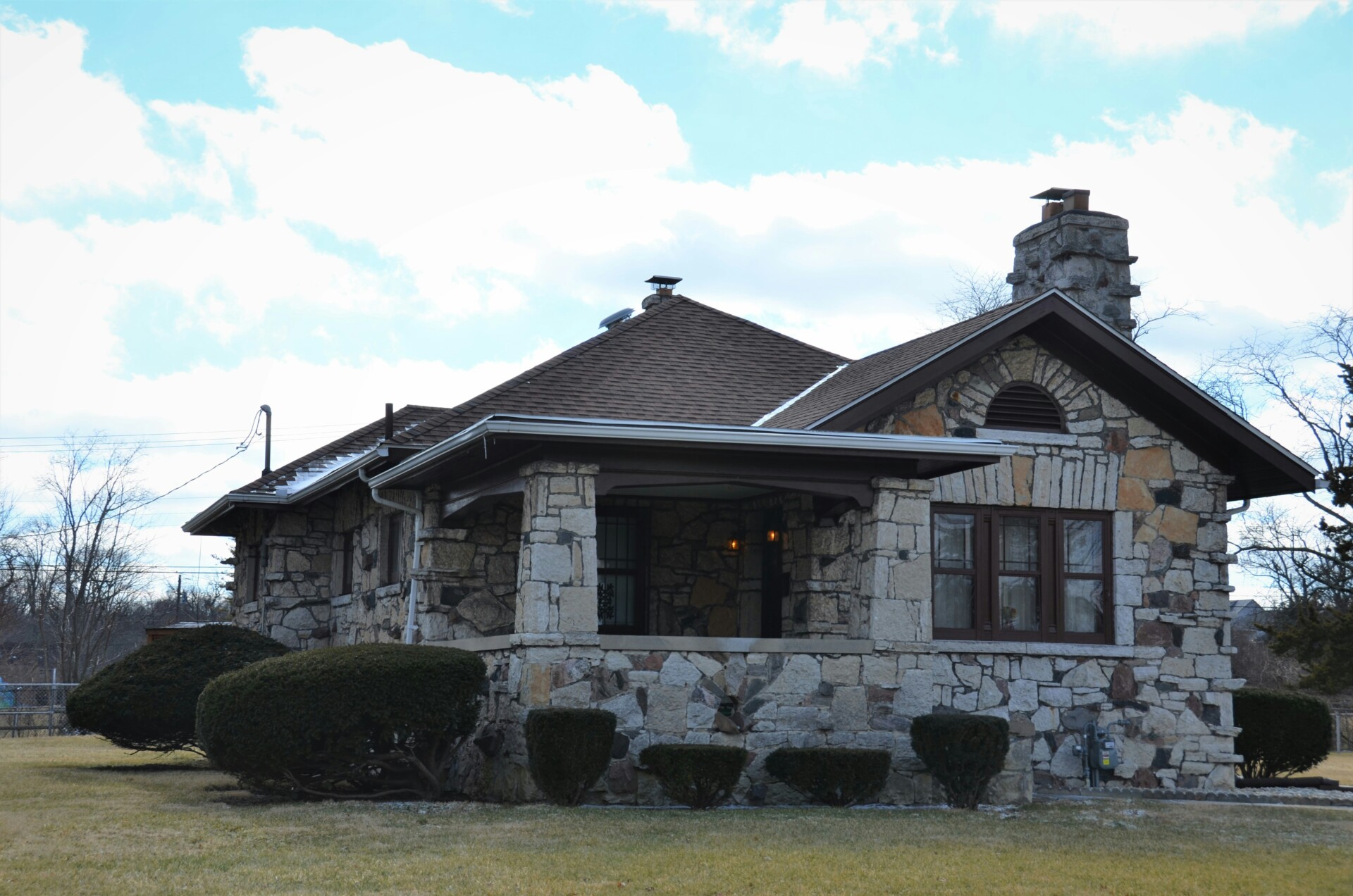 Rustic Stone House A rustic stone house with a sloped roof and a garden in front.