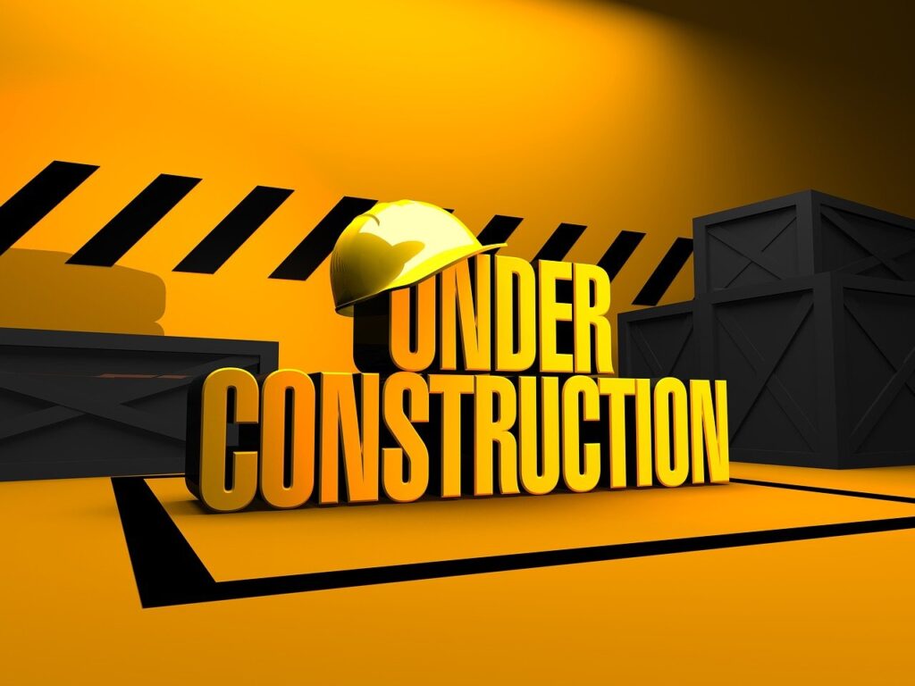 "Yellow 'Under Construction' sign with hard hat against a black and yellow background."