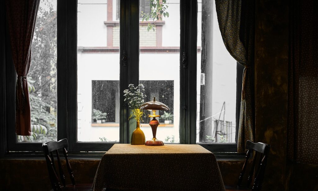 A moody café setting with a vintage lamp and vase on the table.