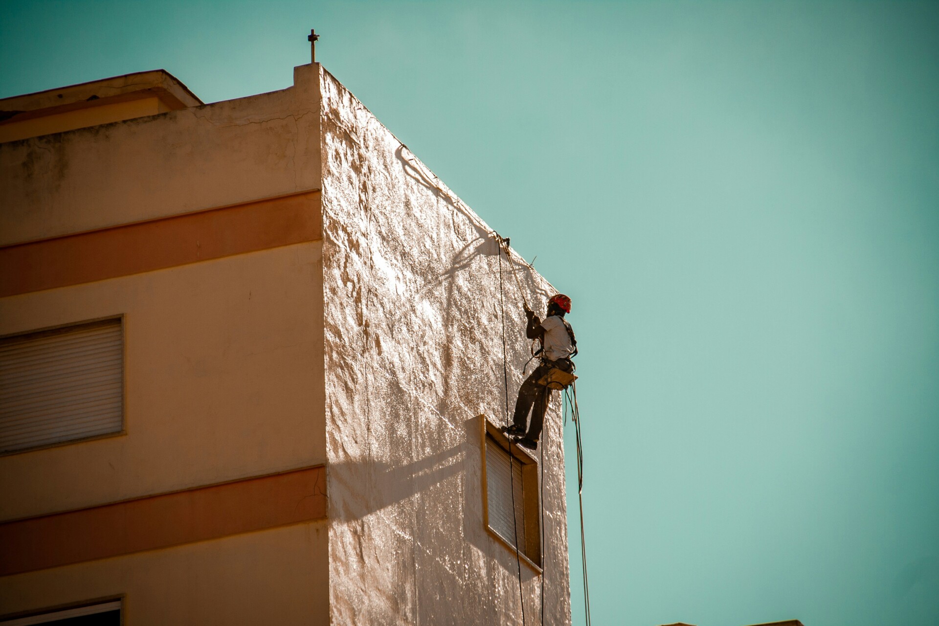 Window Cleaning in Action A window cleaner using ropes to clean the side of a building