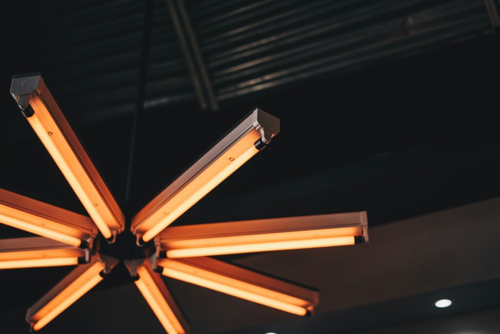A modern orange ceiling light fixture with a fan-like design.