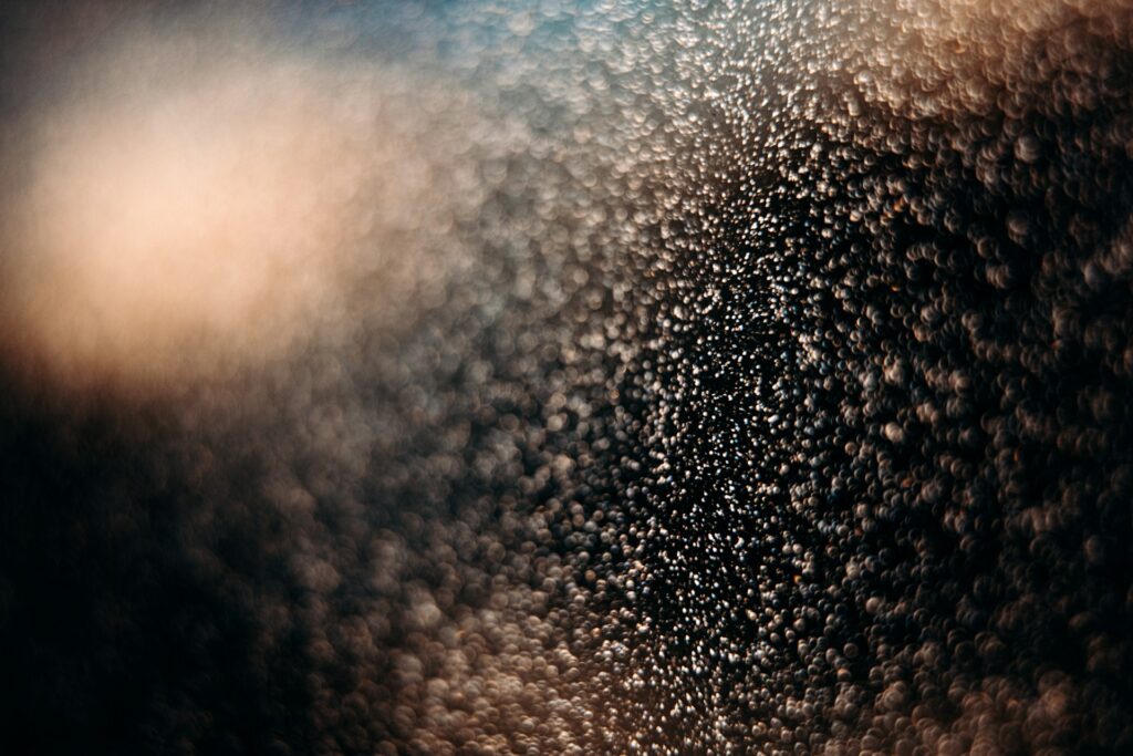 Close-up of water droplets creating a textured, abstract pattern with warm lighting.