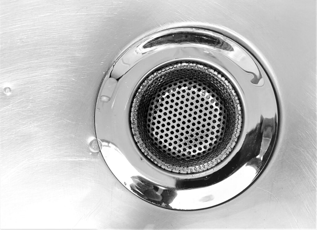 Close-up of a stainless steel sink drain with a metal strainer.