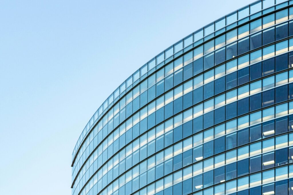Curved modern glass office building under a clear blue sky.