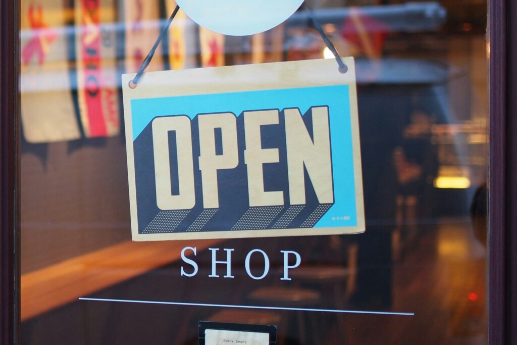 A hanging "OPEN" sign on a shop window, reflecting street and indoor lights.