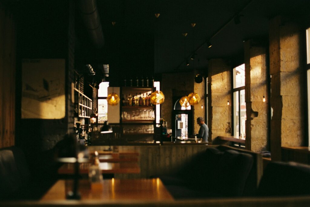 A dimly lit cafe with warm lighting and a lone person at the counter.