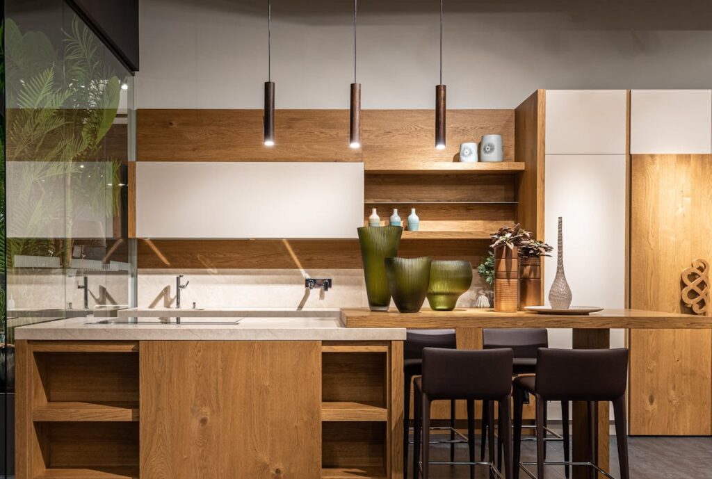 Modern kitchen with wooden cabinets, pendant lights, and decorative elements.