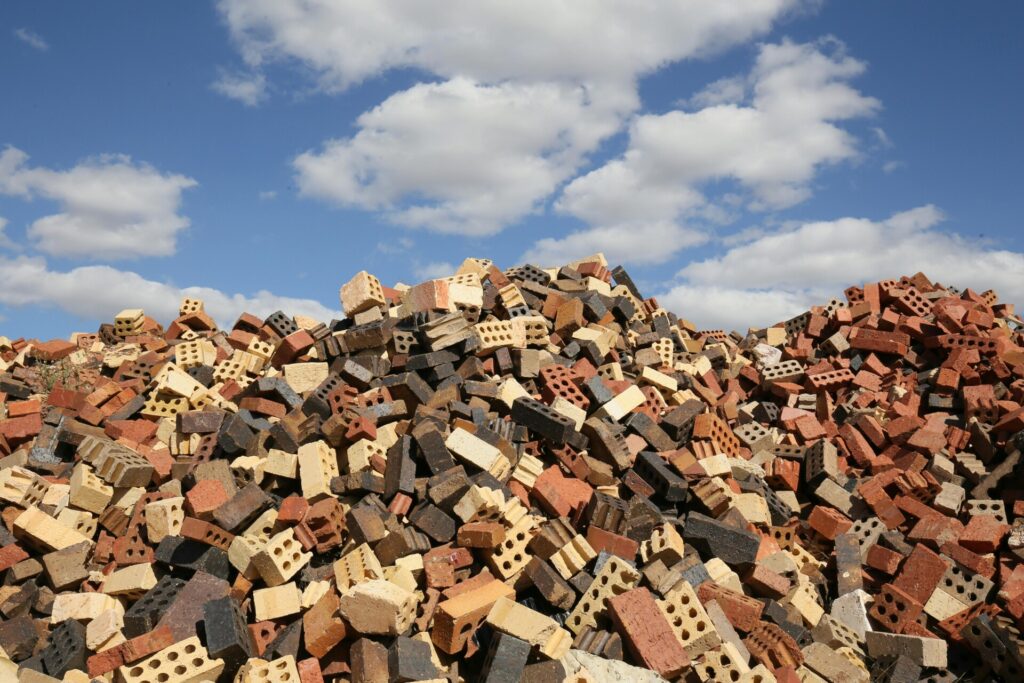 A large pile of colorful bricks under a partly cloudy blue sky.