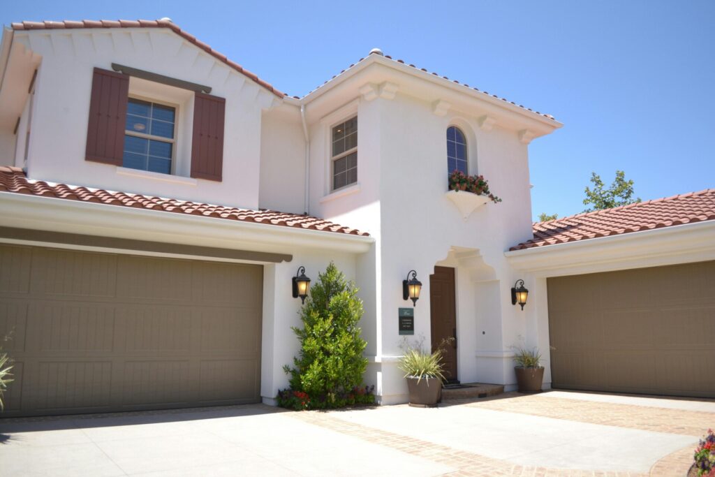 A Mediterranean-style house with beige garage doors and terracotta roof tiles.