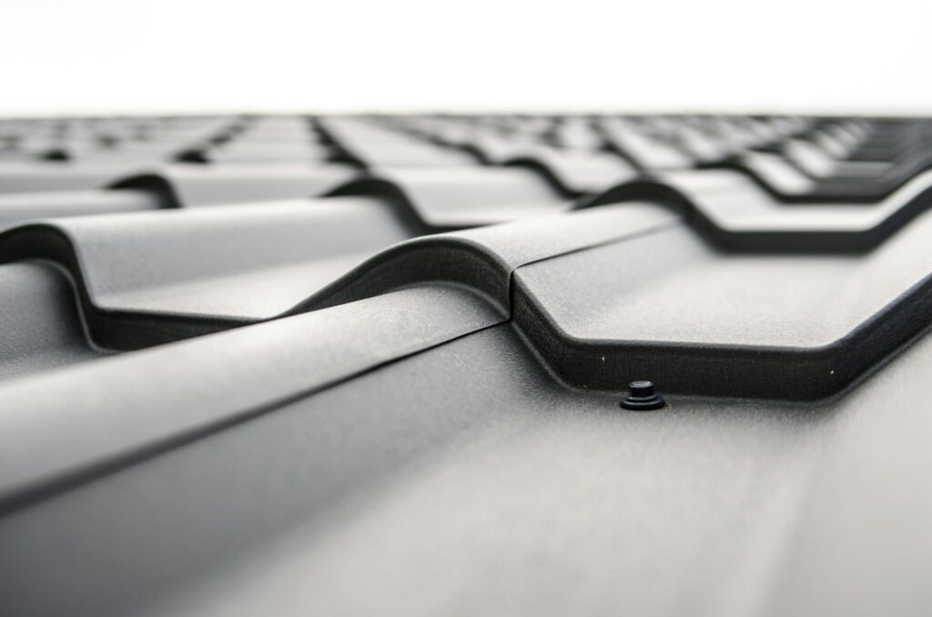 Close-up of a gray metal roof with wavy pattern and fastening screws.