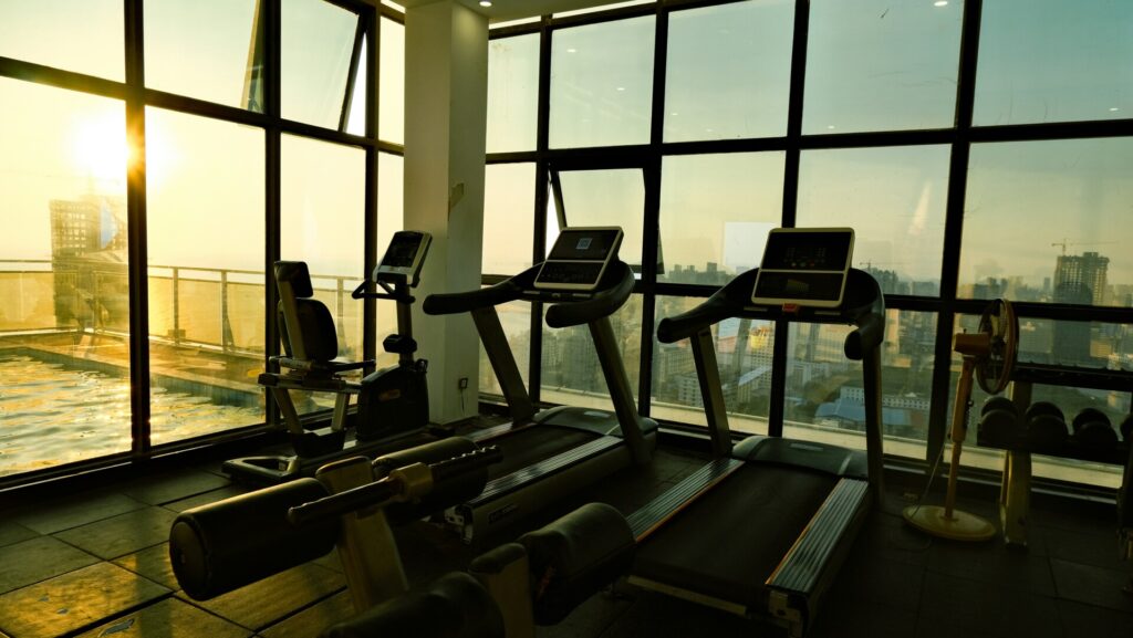 A gym with treadmills and a city view during sunset.