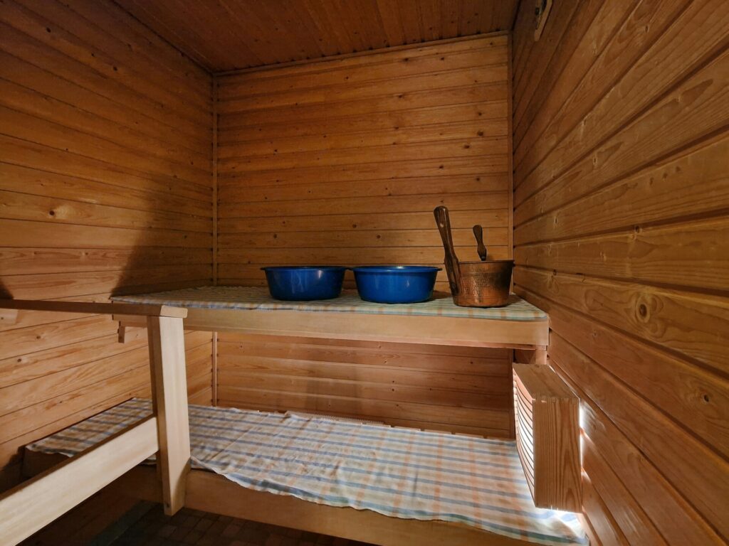 A wooden sauna interior with two basins and a ladle on a bench.