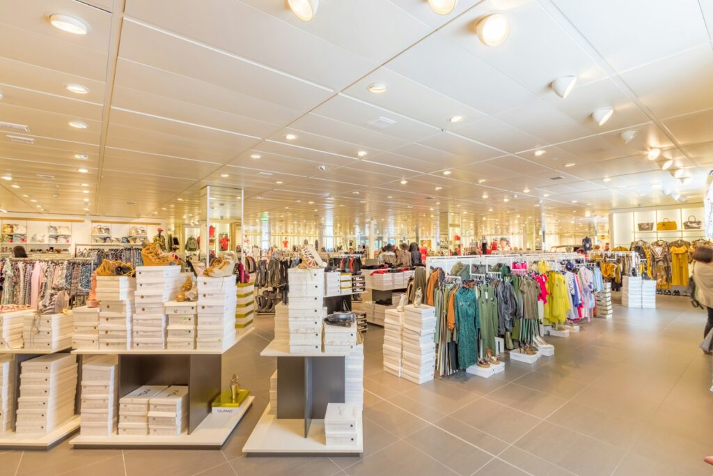 A brightly lit clothing store interior showcasing racks of colorful garments and shoes.