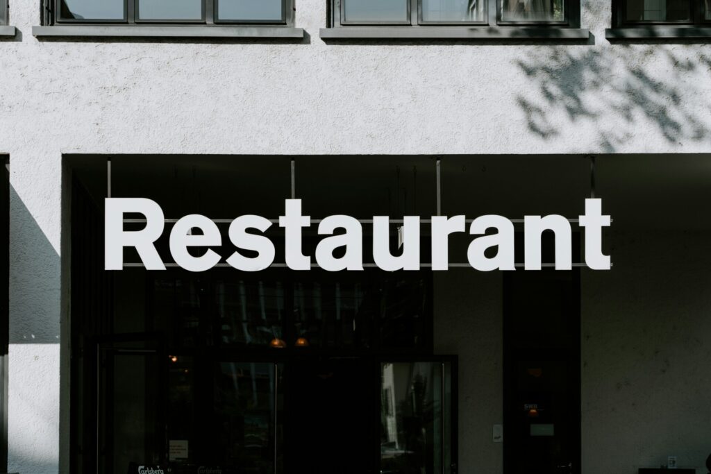 Large white "Restaurant" sign on a building facade with windows above.
