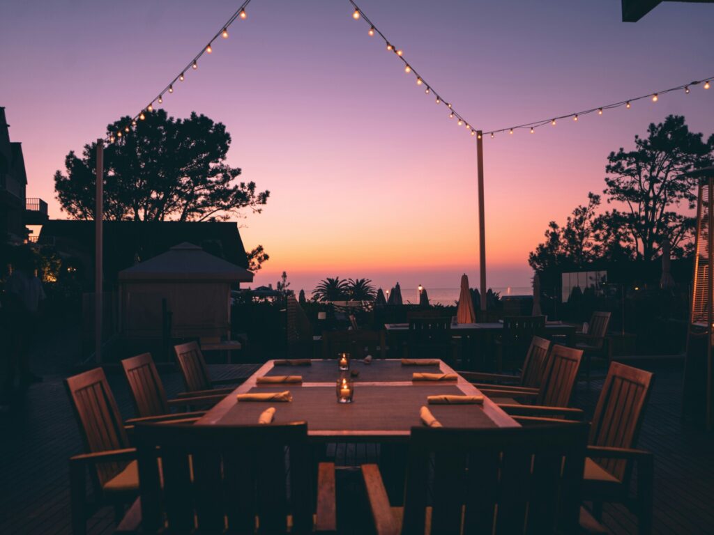 Outdoor dining area with a vibrant sunset and string lights.