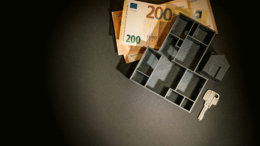 Model house and euro notes with a key on a dark background.