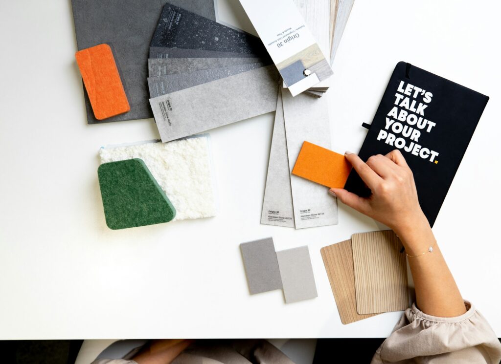 Person selecting color swatches on a table with design materials.