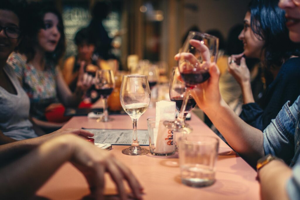 People enjoying a lively dinner party with glasses of wine at a restaurant.