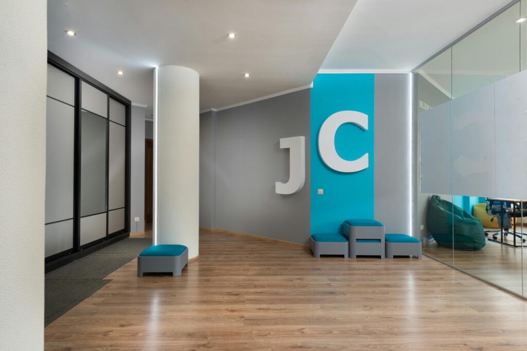 Modern office interior with "JC" logo on a teal and gray wall.