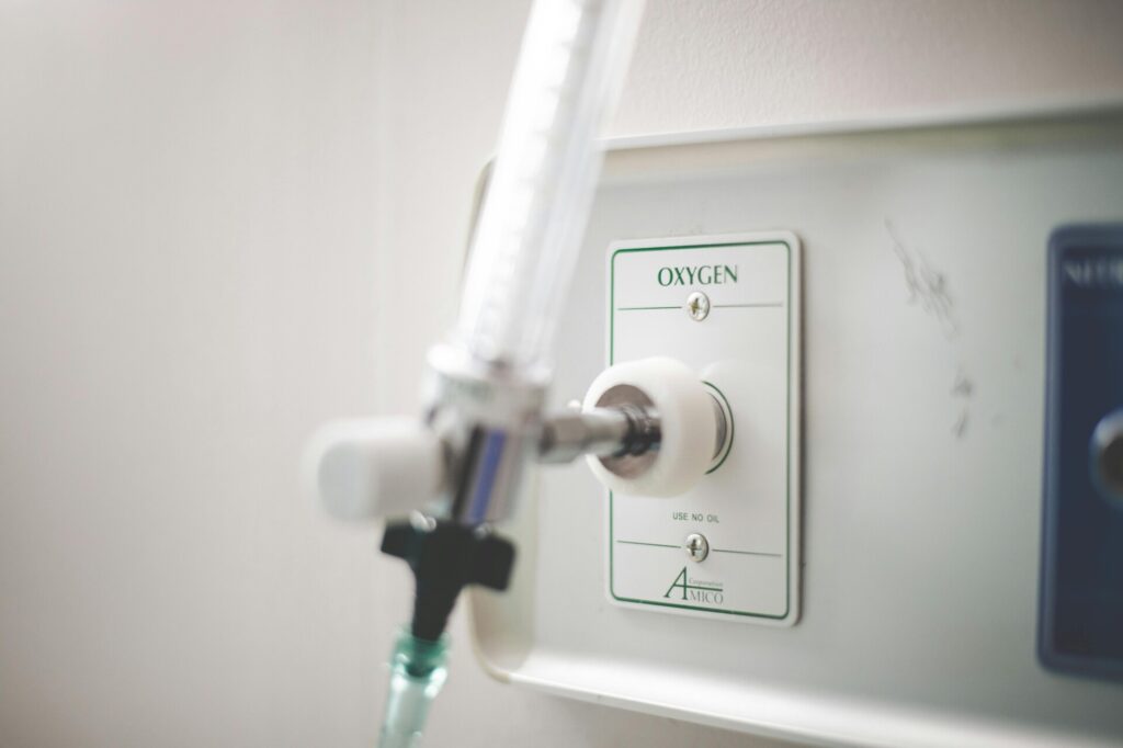 Close-up of an oxygen outlet in a medical setting with attached tubing.
