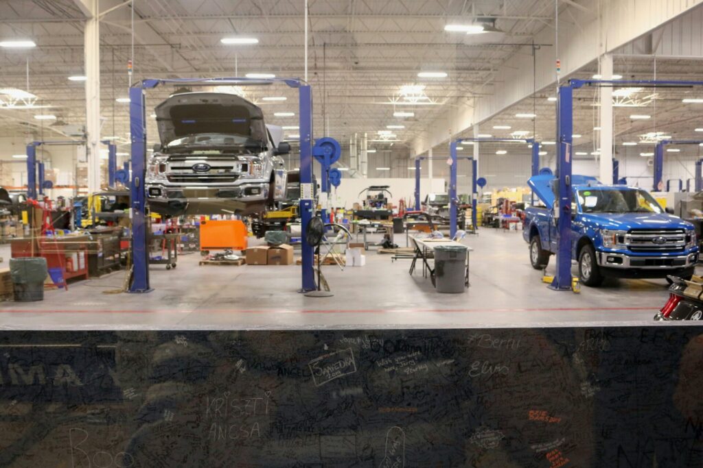 A car repair shop with vehicles lifted on hydraulic platforms inside a spacious garage.