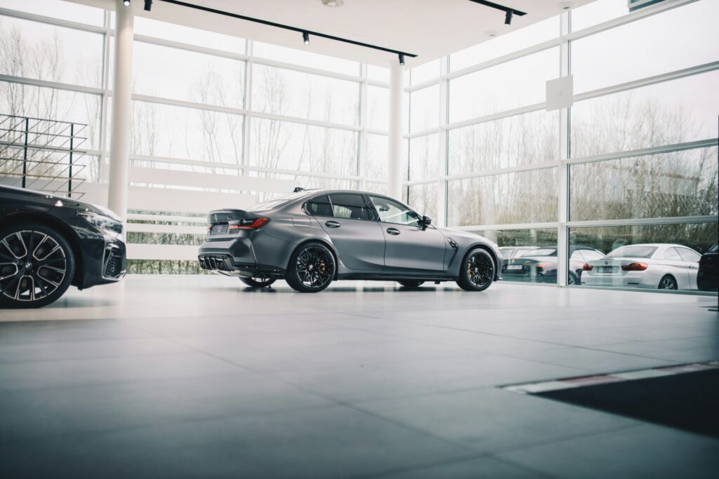 A sleek silver car inside a modern glass-walled showroom with other vehicles.